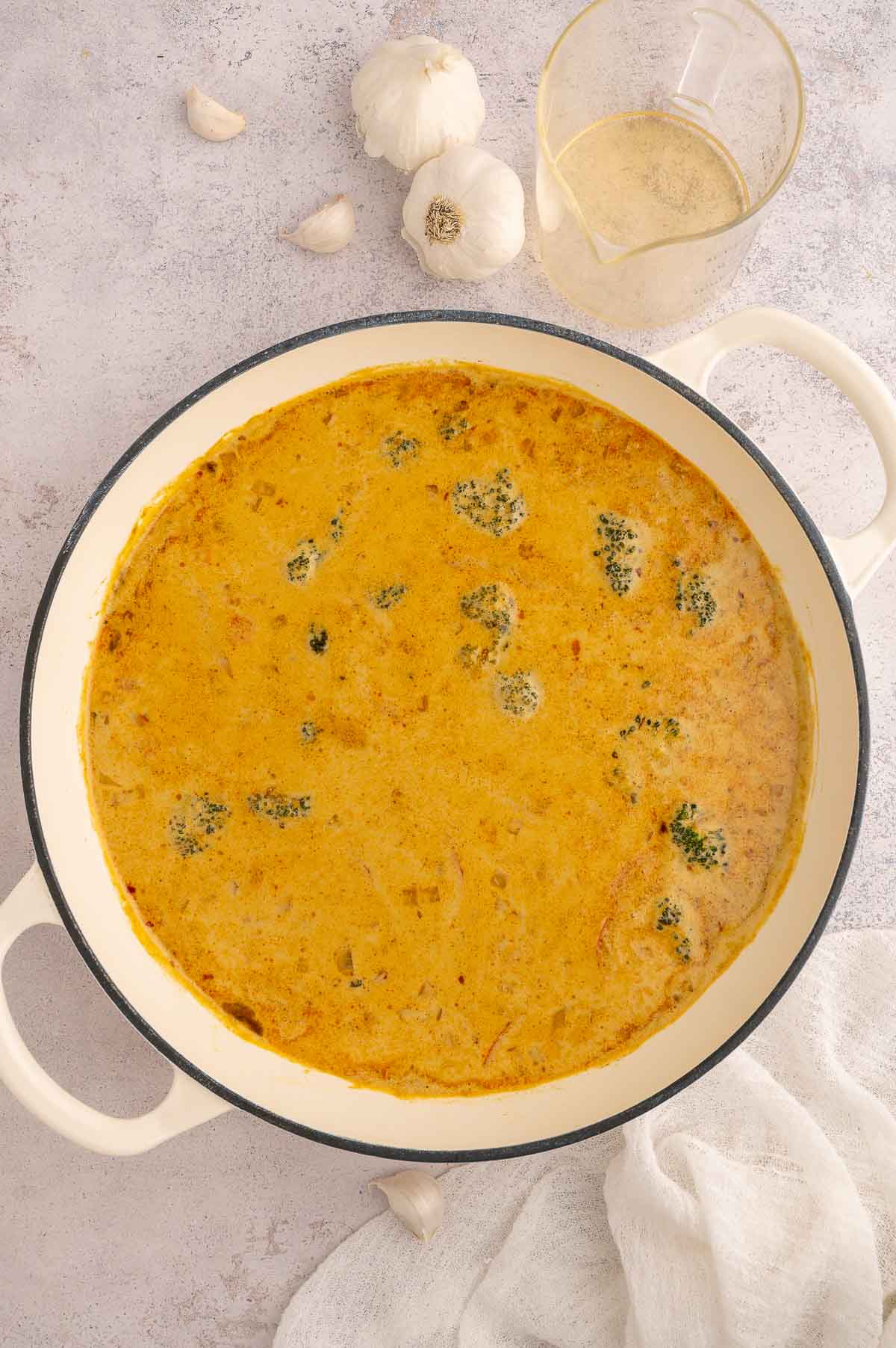 Large pot of Thai-style vermicelli noodle soup with coconut curry broth and broccoli.