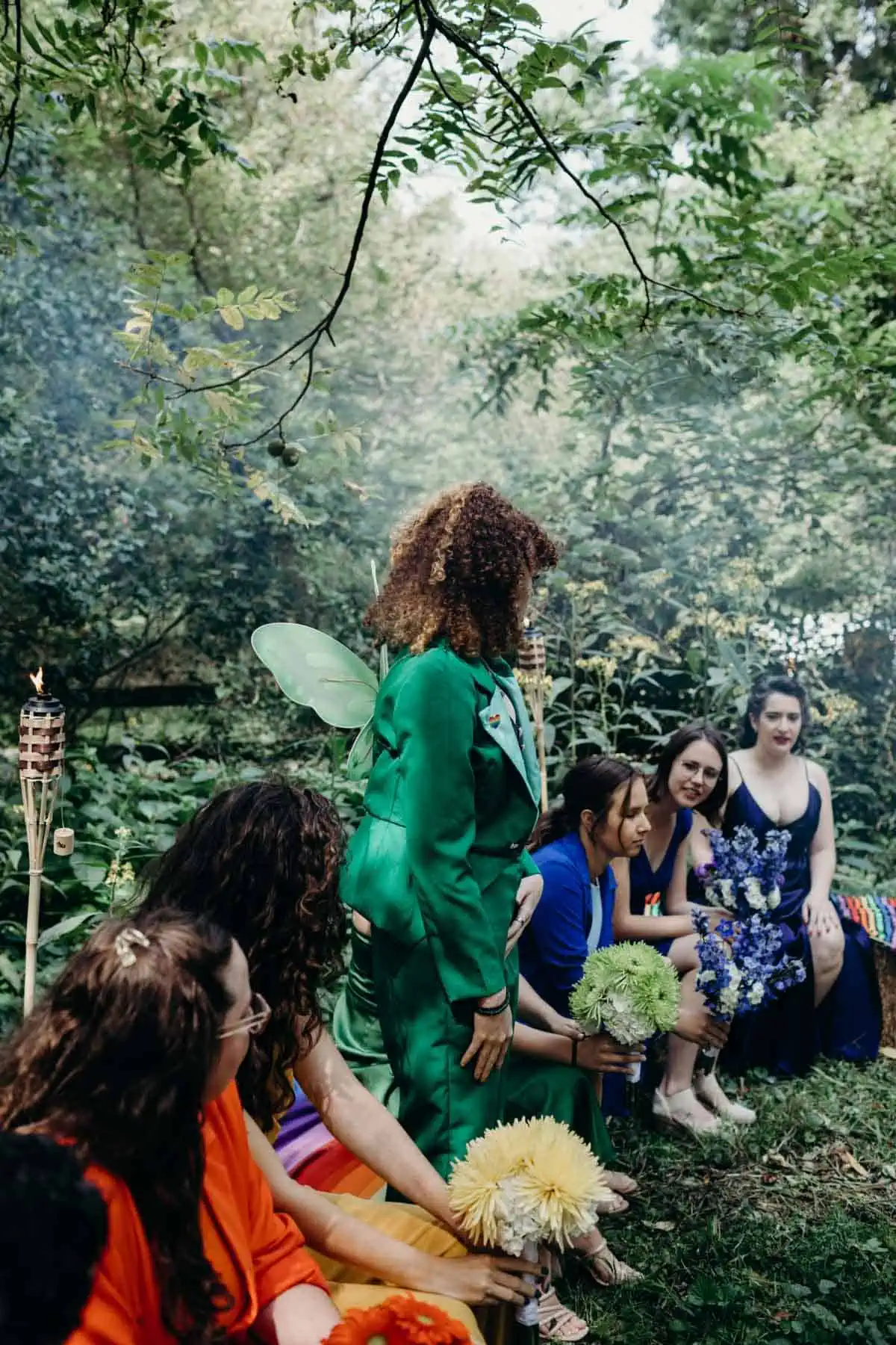 Woodland rainbow wedding with guests seated in colorful outfits.